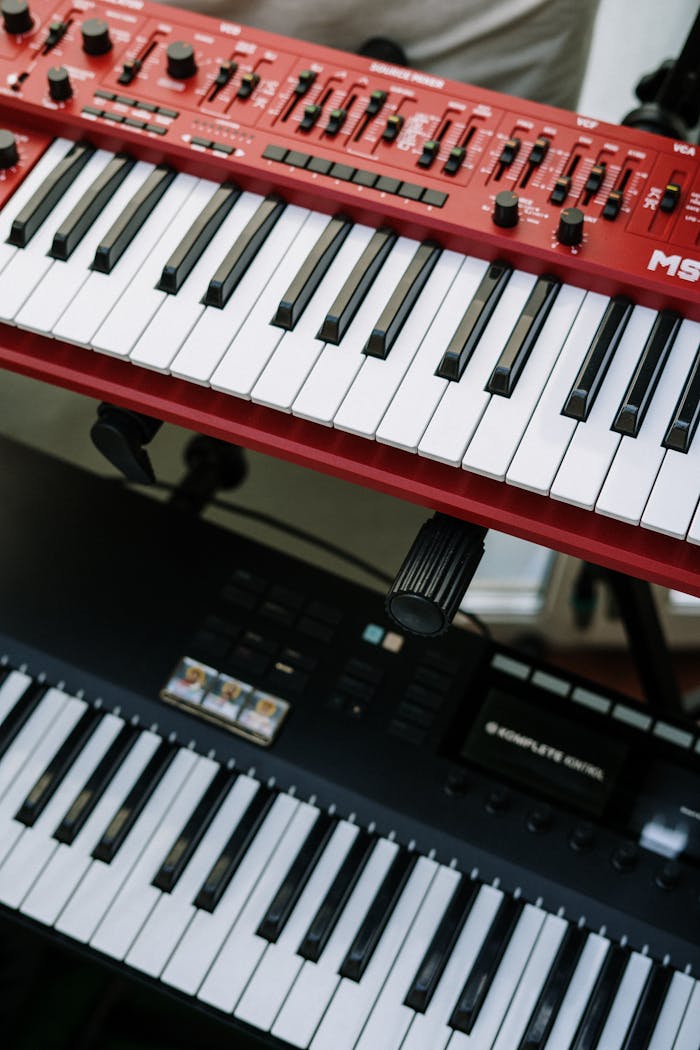 About Vertical shot of red and black electronic keyboards in a home studio setting.